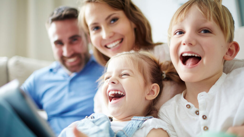 family of four sitting on the couch laughing